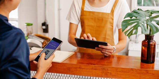 Man paying by phone in a small store using a scannable QR code